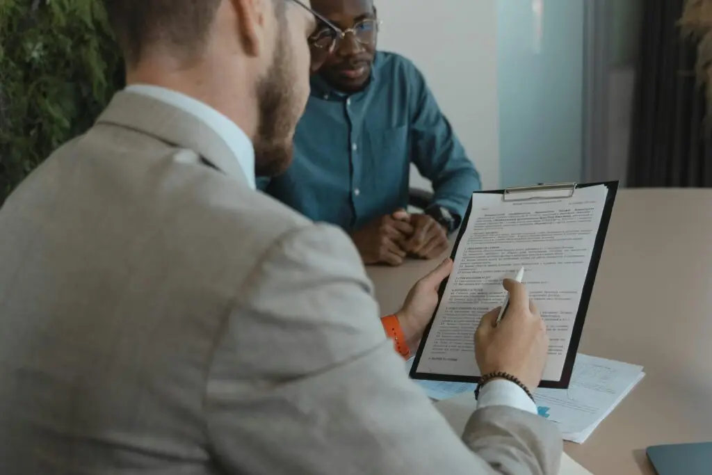 A recruiter reviews a candidate's documents during a job interview in a modern office setting.
